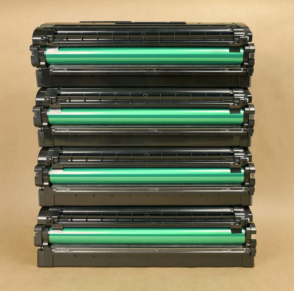 Four laser toner cartridges stacked, showing their imaging drums